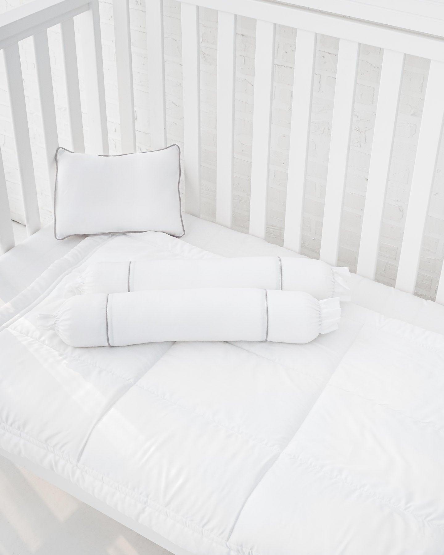 White crib with white organic bamboo lyocell baby bedding (baby comforter set - 1 pillowcase, 2 bolstercases, 1 comforter; baby pillow set - 1 headshaping pillow, 2 bolsters; crib fitted sheet)