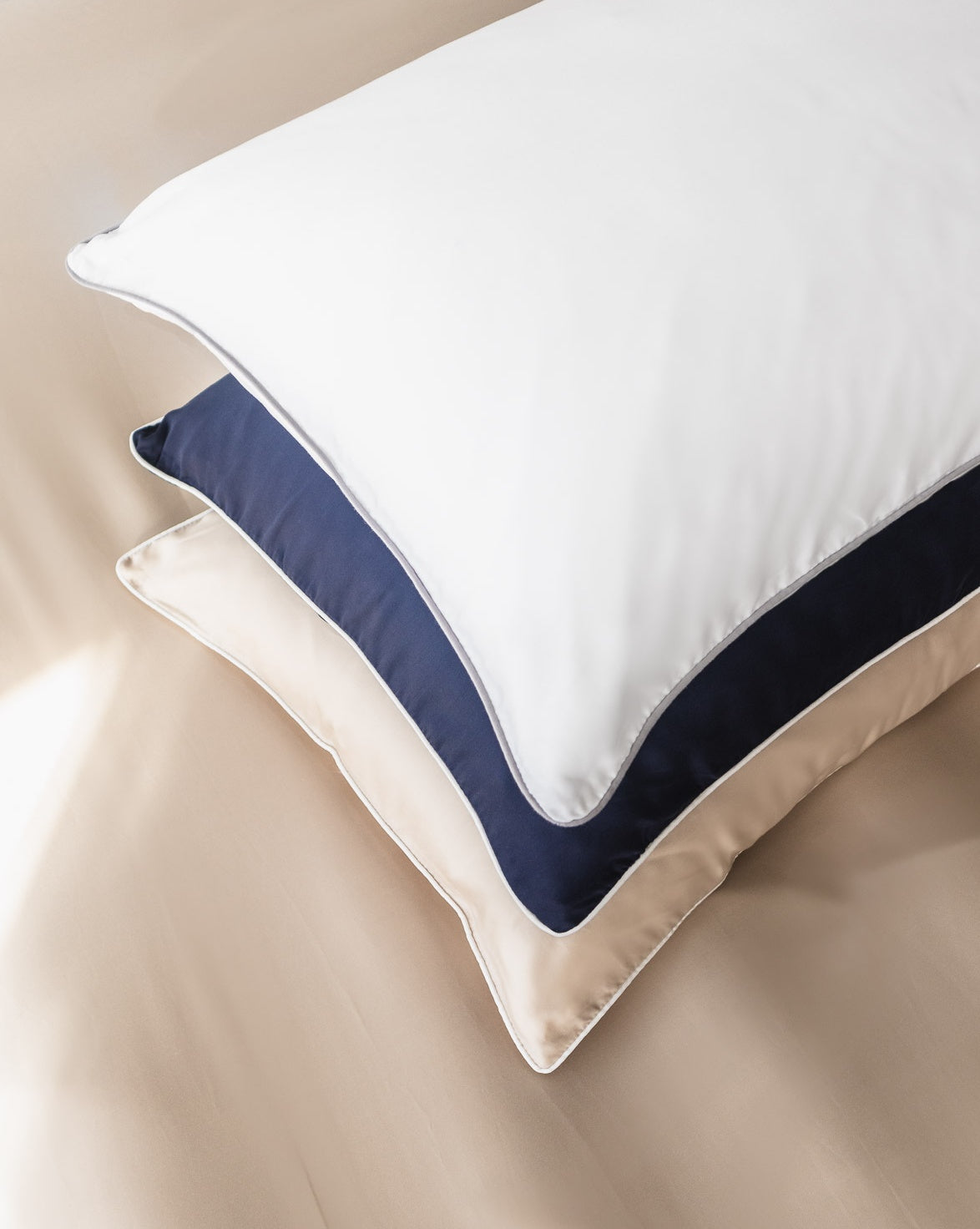 stack of vegan silk pillowcases, organic bamboo lyocell pillowcases white, beige sand, navy blue with white piping