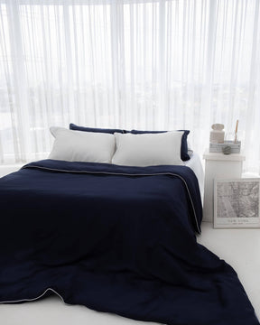 organic bamboo lyocell duvet cover and sheet set (fitted sheet and pillowcases) in silver lining (white with gray piping) and ocean (navy with white piping). ava and ava ph soft and cooling bedding sheets.