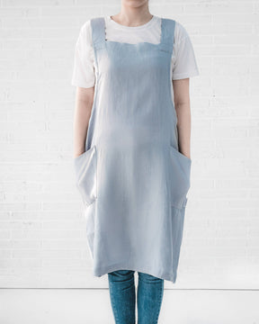 ava and ava ph Light sky blue pure linen crossback apron on female adult, hands on side pockets