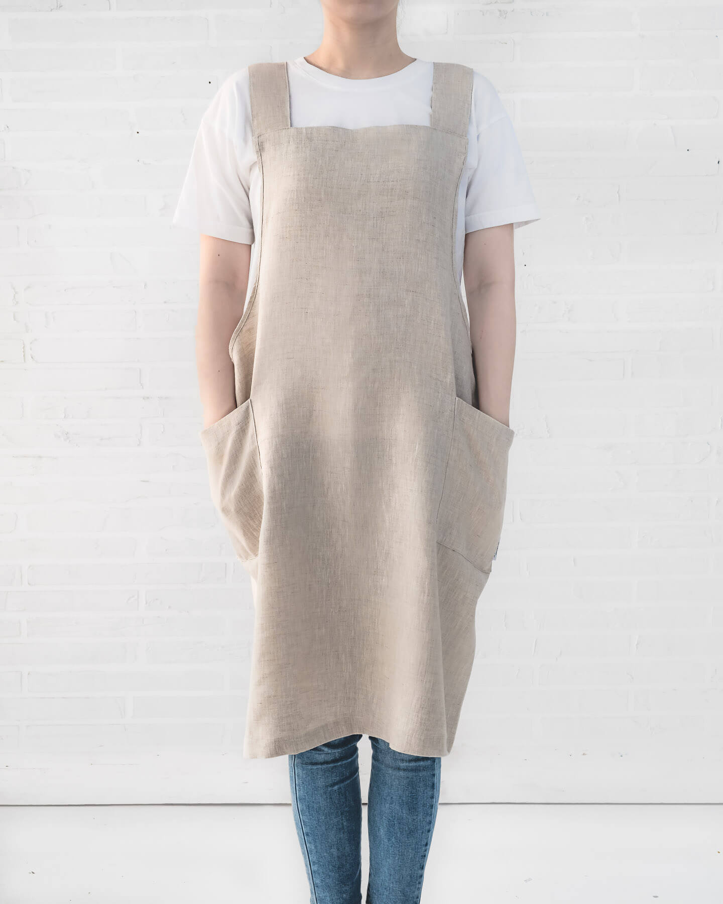 ava and ava ph natural color pure linen crossback apron on female adult, hands on side pockets