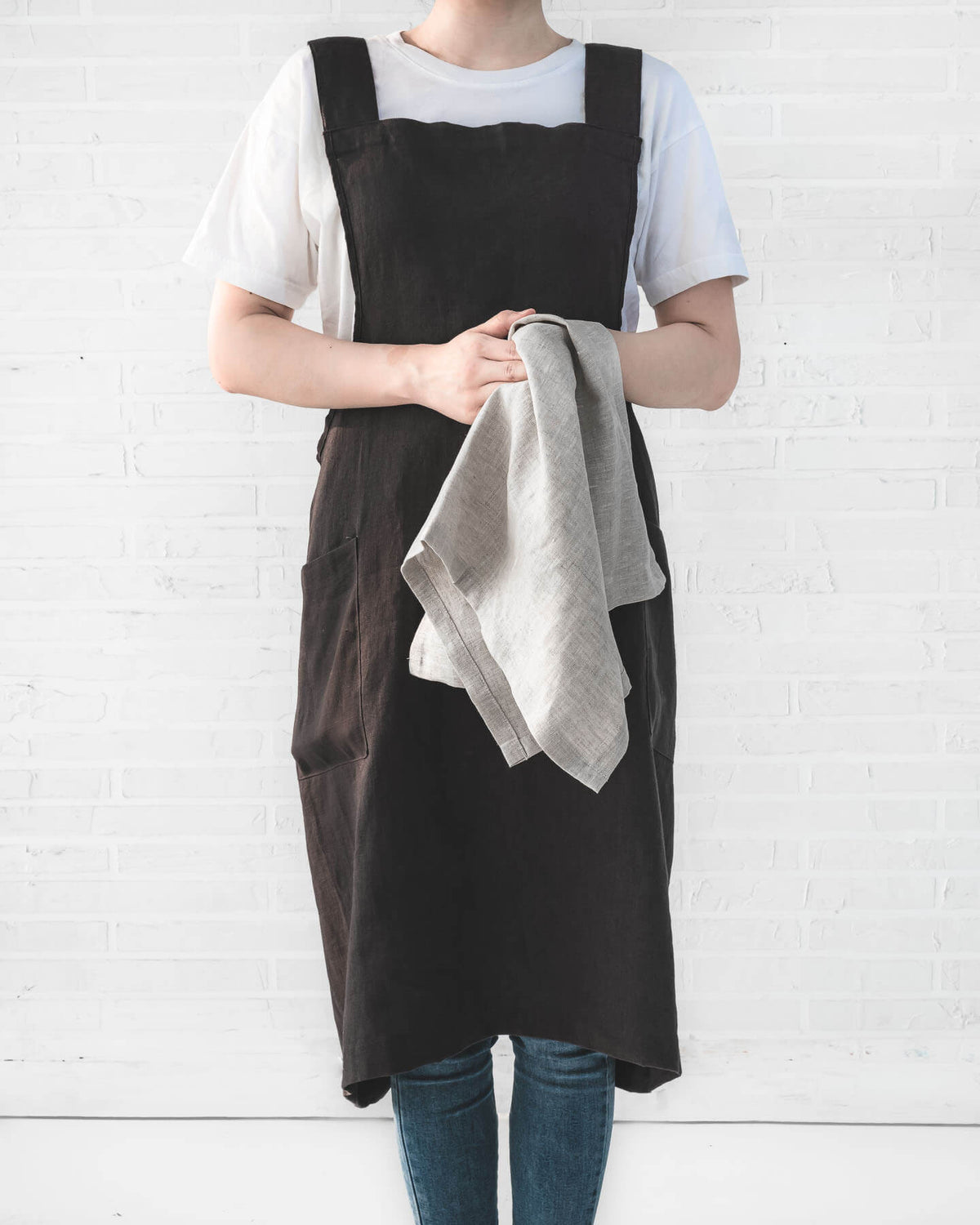 ava and ava ph Charcoal pure linen crossback apron on female adult, holding linen tea towel