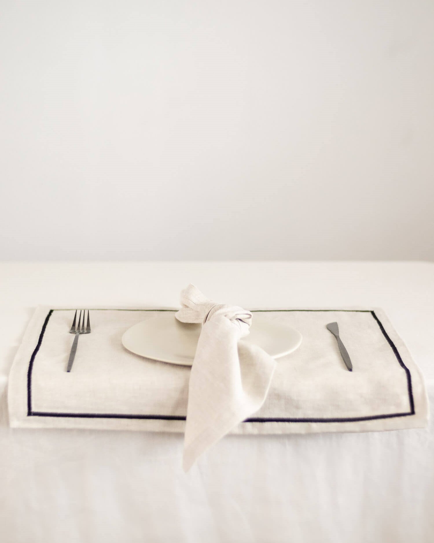 ava and ava natural pure linen placemat with black embroidered border, with white linen napkin, white plate, silver wood cutlery
