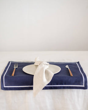 ava and ava Blue pure linen placemat with white embroidered border, with white linen napkin, white plate, silver wood cutlery