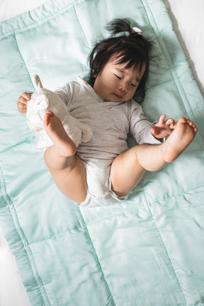 Baby sleeping on mint green organic bamboo lyocell comforter