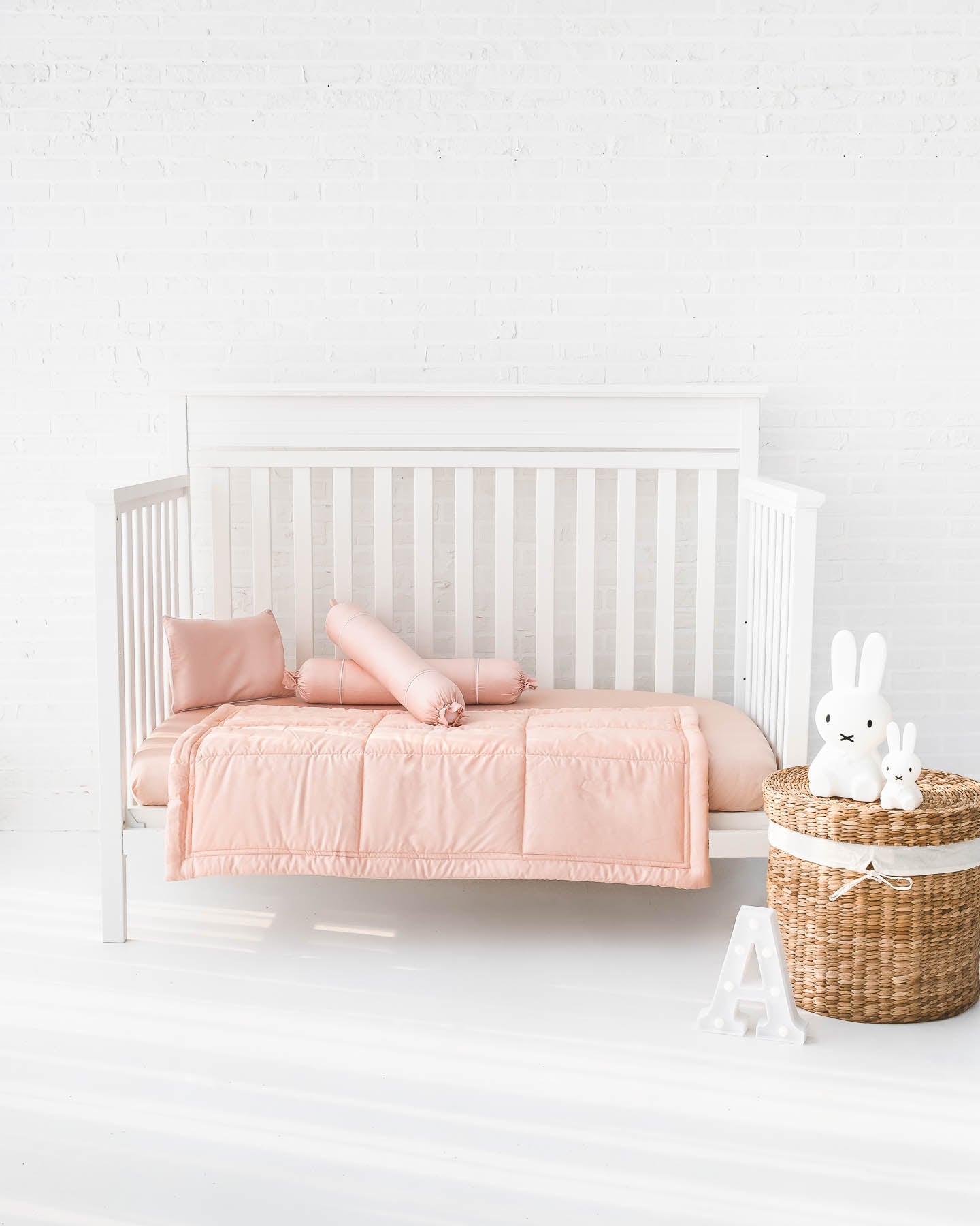 White crib with blush peach pink organic bamboo lyocell baby bedding (baby comforter set - 1 pillowcase, 2 bolstercases, 1 comforter; baby pillow set - 1 headshaping pillow, 2 bolsters; crib fitted sheet)